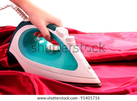 Electric iron on red cloth isolated on white