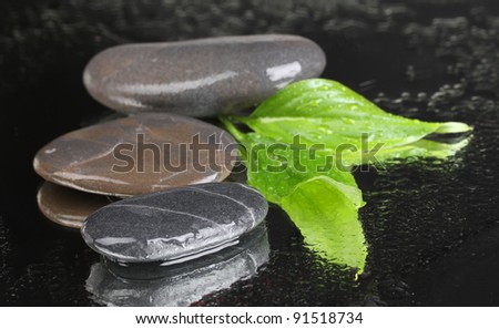 spa stones with water drops and leaves on black background
