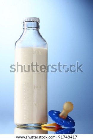 bottle of milk and soother on blue background