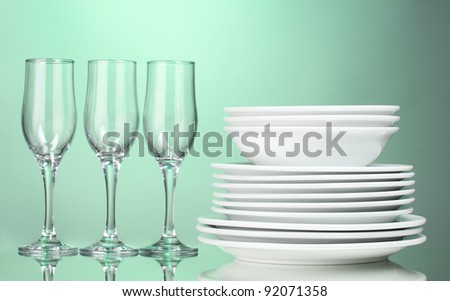 Clean plates and glasses on green background