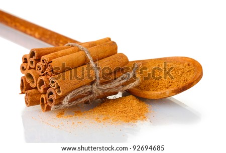 Cinnamon sticks and powder in wooden spoon isolated on white
