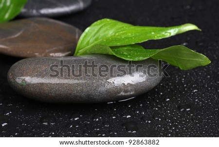 spa stones with water drops and leaves on black background