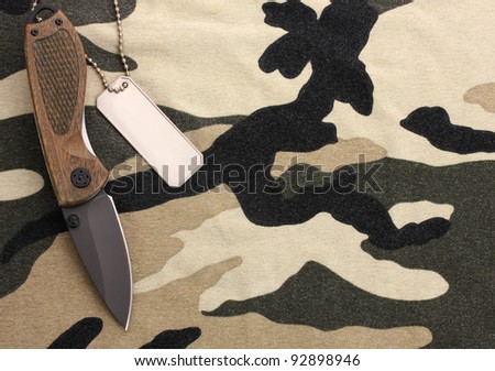 Army badges and knife on camouflage background