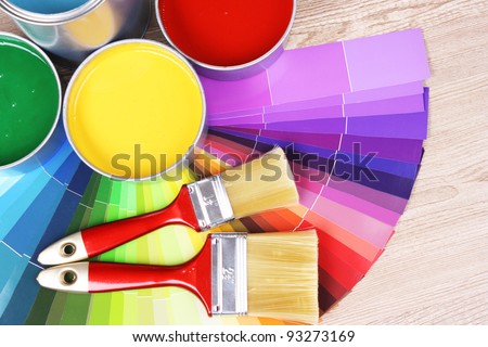 open tin cans with paint and palette on wooden background