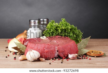 raw meat, vegetables and spices on gray background