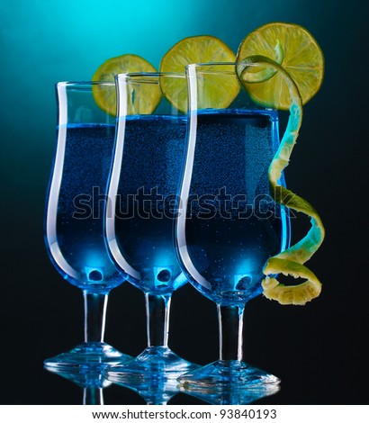 Blue cocktail in glasses with lime on blue background