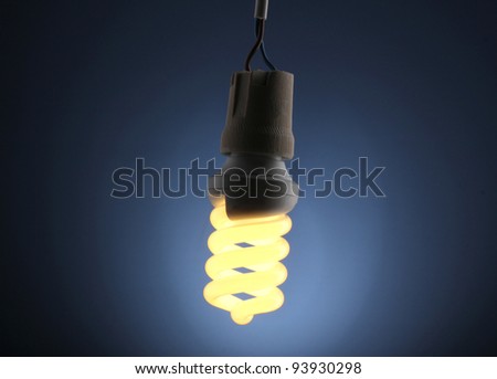 A lit energy saving light bulb on blue background
