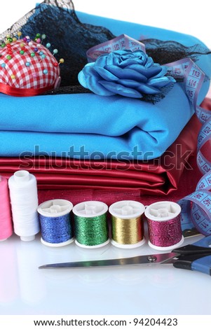 red, blue and pink thread, measuring tape and fabric isolated on white