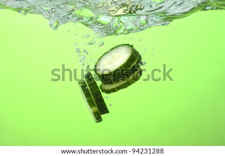 fresh sliced cucumber in water on green background
