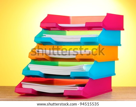 bright paper trays on wooden table on yellow background