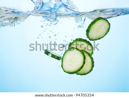 fresh sliced cucumber in water on blue background