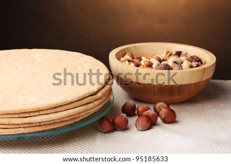 cakes for cake on glass stand and nuts on wooden table on brown background