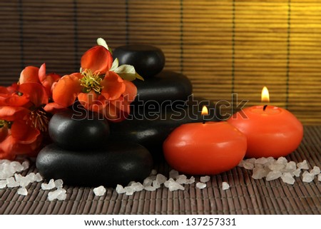 Spa stones with flowers and candles on bamboo background