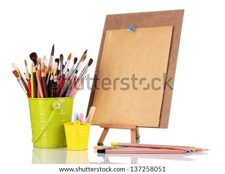 Small easel with sheet of paper with art supplies isolated on white