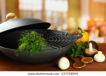 Black wok pan and vegetables on kitchen wooden table, close up