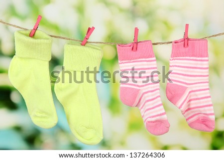 Colorful socks hanging on clothesline, on bright background
