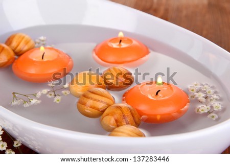 Beautiful candles swim in beautiful plate on wooden table close-up