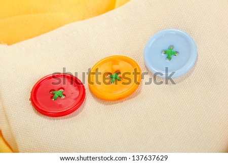 Three buttons on beige and yellow cloth
