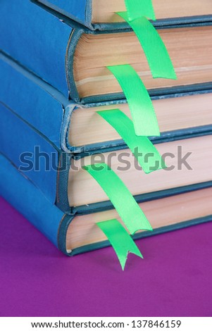 Many books with bookmarks on purple background close-up