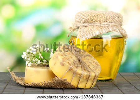 Hand made soap and ingredients for soap making on bamboo mat, on green background