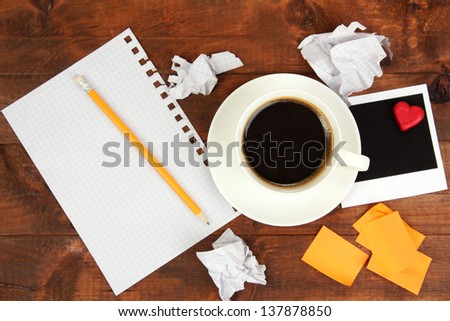 Cup of coffee on worktable covered with photo frames and stickers close up