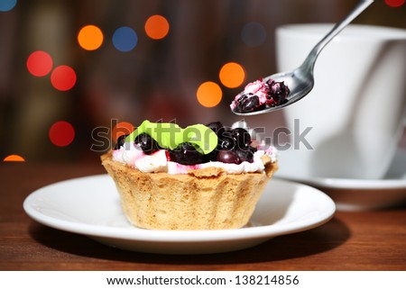 Tasty blackberry cake and cup of beverage,  on dark background with bokeh  defocused lights