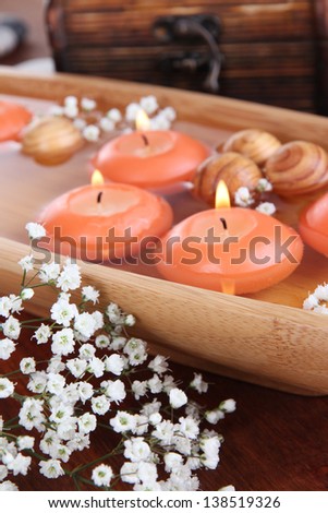 Beautiful candles in water on wooden table close-up