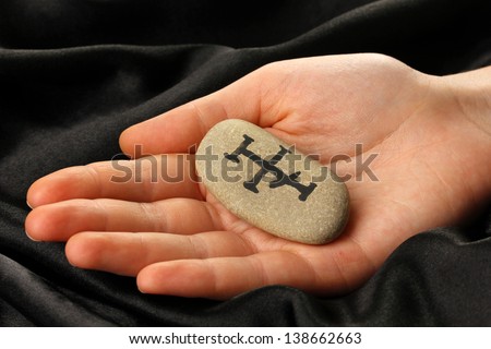 Fortune telling  with symbols on stone in hand on black fabric background
