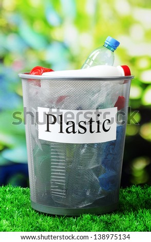 Assorted trash in bucket on nature background