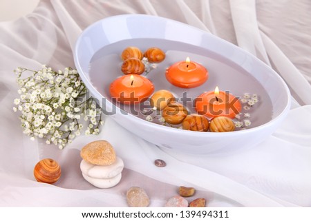 Beautiful candles swim in beautiful plate on wooden table close-up