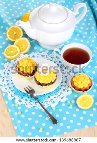 Beautiful lemon cupcakes and flavored tea on dining table close-up