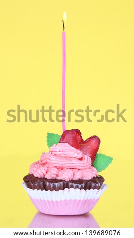 Beautiful cupcake with candle on yellow background