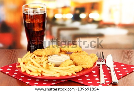 Fried chicken nuggets with french fries,cola and sauce on table in cafe