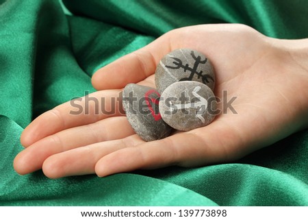 Fortune telling  with symbols on stone in hand on green fabric background