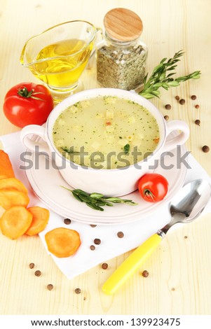 Nourishing soup in pink pan with ingredients on wooden table close-up