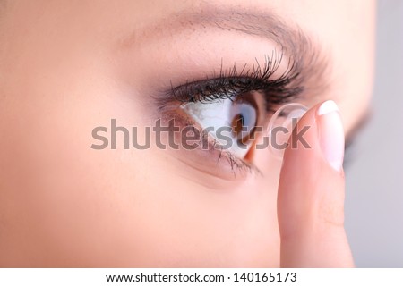Young Woman Putting Contact Lens In Her Eye Close Up