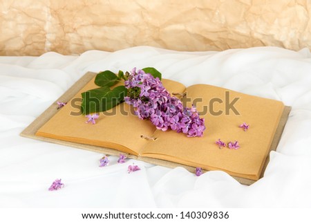 Lilacs branch on book on white fabric background