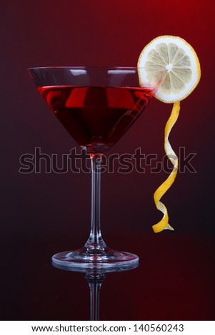 Red cocktail in martini glass on dark red background