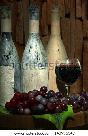 Composition with old bottles of wine and wineglass in old cellar, on dark  background