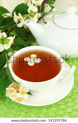 Cup of tea with jasmine, on wicker mat background
