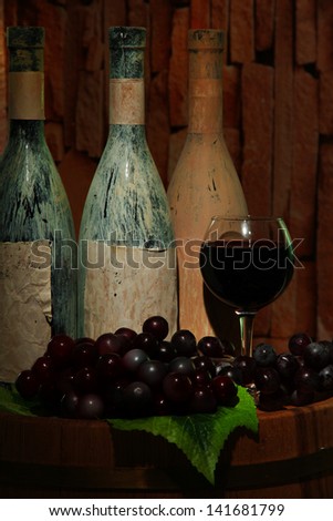 Composition with old bottles of wine and wineglass in old cellar, on dark  background