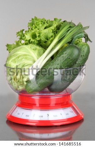 Fresh vegetables in scales on gray background