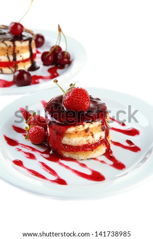 Tasty biscuit cakes with jam and berries on plates, isolated on white