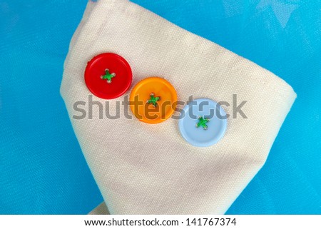 Three buttons on beige and blue cloth