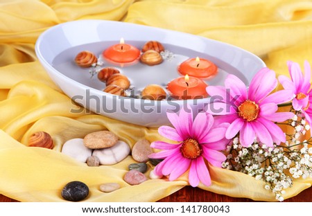 Beautiful candles swim in beautiful plate on yellow fabric close-up