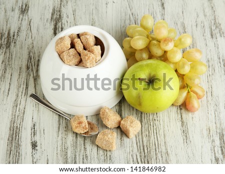 Unrefined sugar in white sugar bowl on wooden background