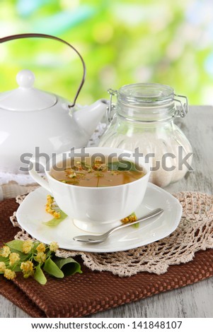 Cup of tea with linden on napkins on    wooden table on nature background