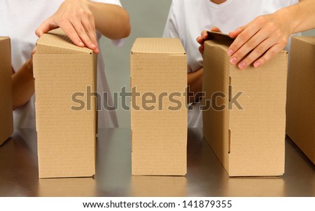 Workers working with boxes at conveyor belt, on grey background