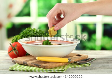 Bowl of soup with bouillon cube on wooden table