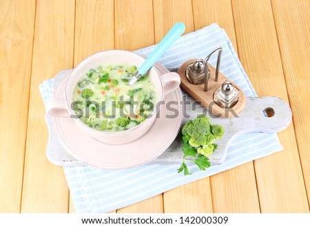 Cabbage soup in plate on napkin on board for cutting on wooden table